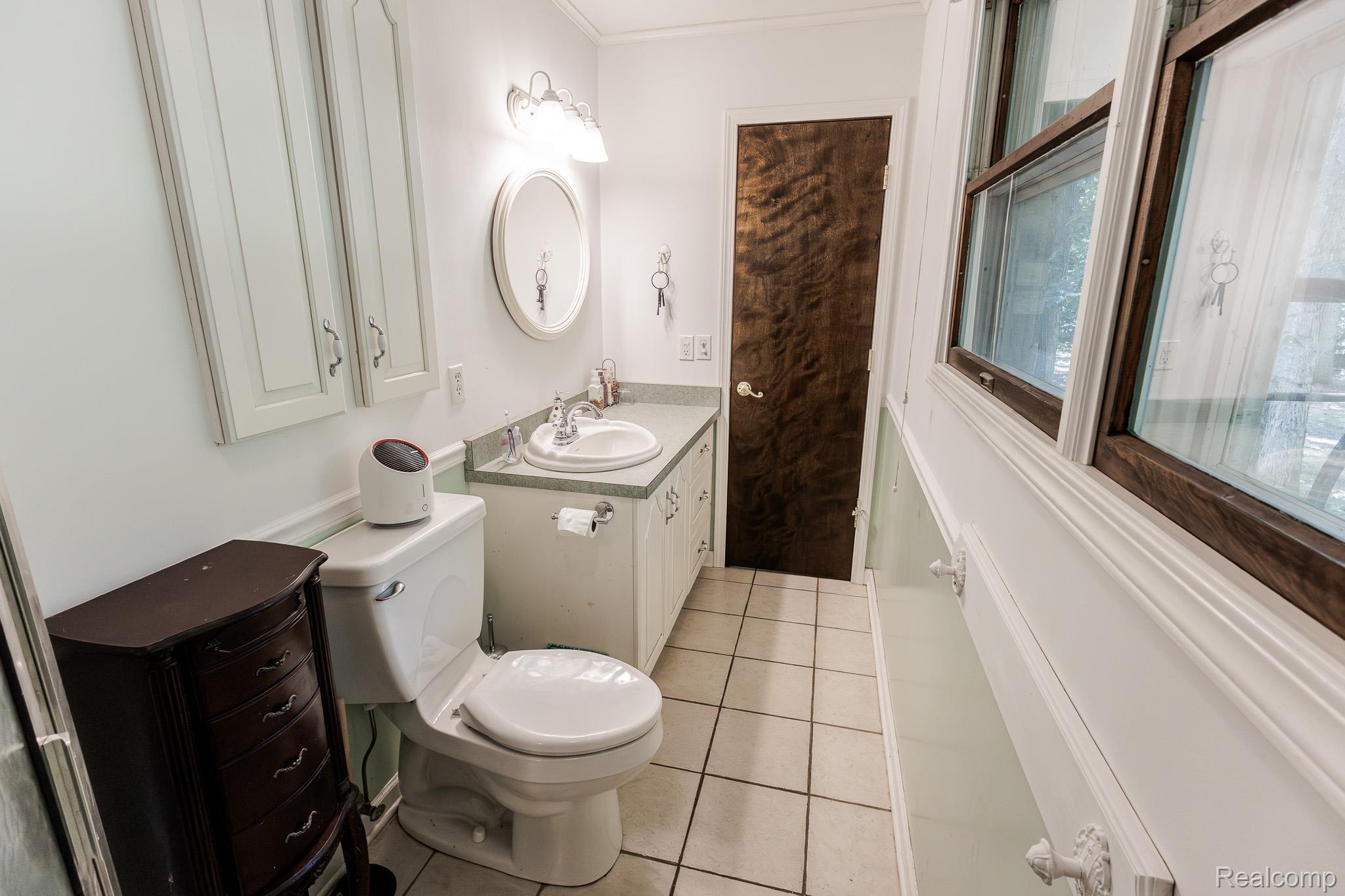 8197 Irish Road Millington, MI 48746 - Photo 27 of 38 Bathroom featuring a white toilet, light-colored tile flooring, and a vanity with a built-in sink and light-toned countertop