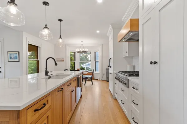 a large kitchen with stainless steel appliances granite countertop a stove and a sink with wooden floor