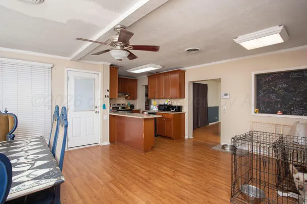 a kitchen with stainless steel appliances kitchen island granite countertop a refrigerator a stove a sink a dining table and chairs with wooden floor