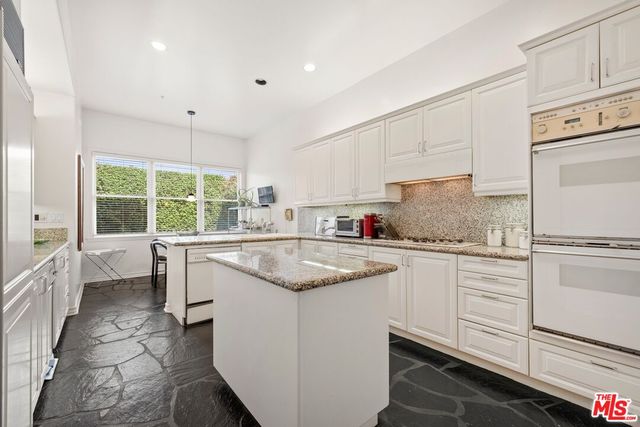 a kitchen with granite countertop white cabinets and white appliances