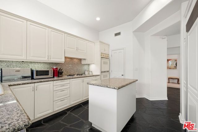 a kitchen with granite countertop white cabinets and white appliances