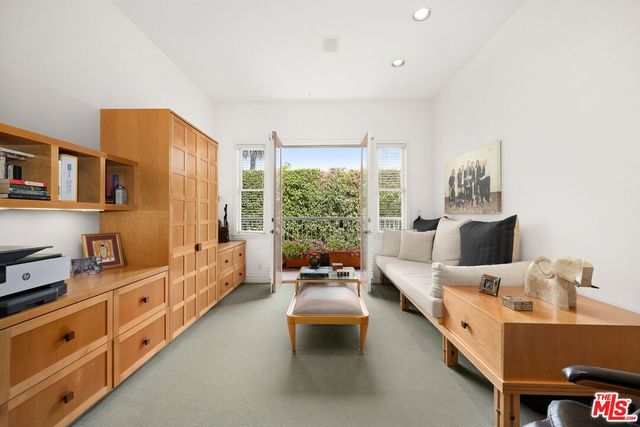 a large white bed sitting in a living room next to a window