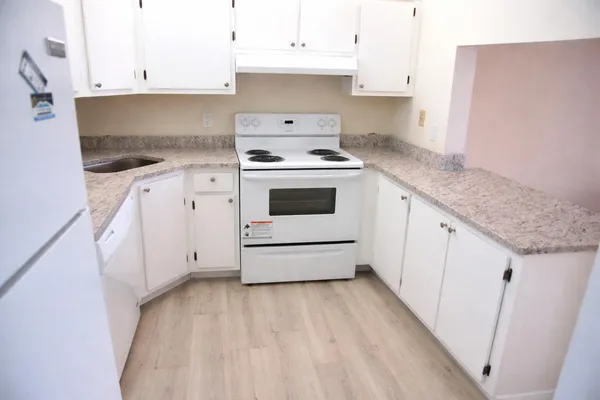 a kitchen with granite countertop white cabinets and white appliances