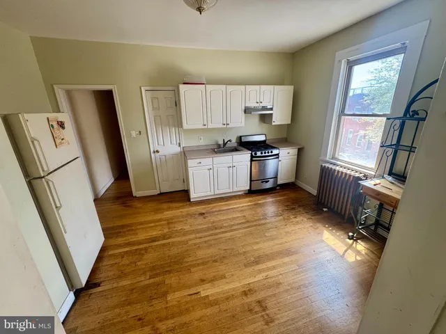 a view of an empty room with window and wooden floor