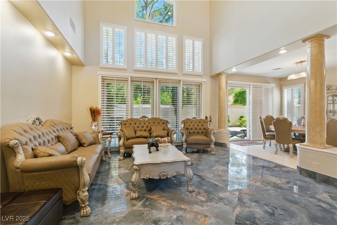 8215 Crow Valley Lane Las Vegas, NV 89113 - Photo 13 of 43 Living room with marble tiled flooring, healthy amount of natural light, a high ceiling, decorative columns, and recessed lighting