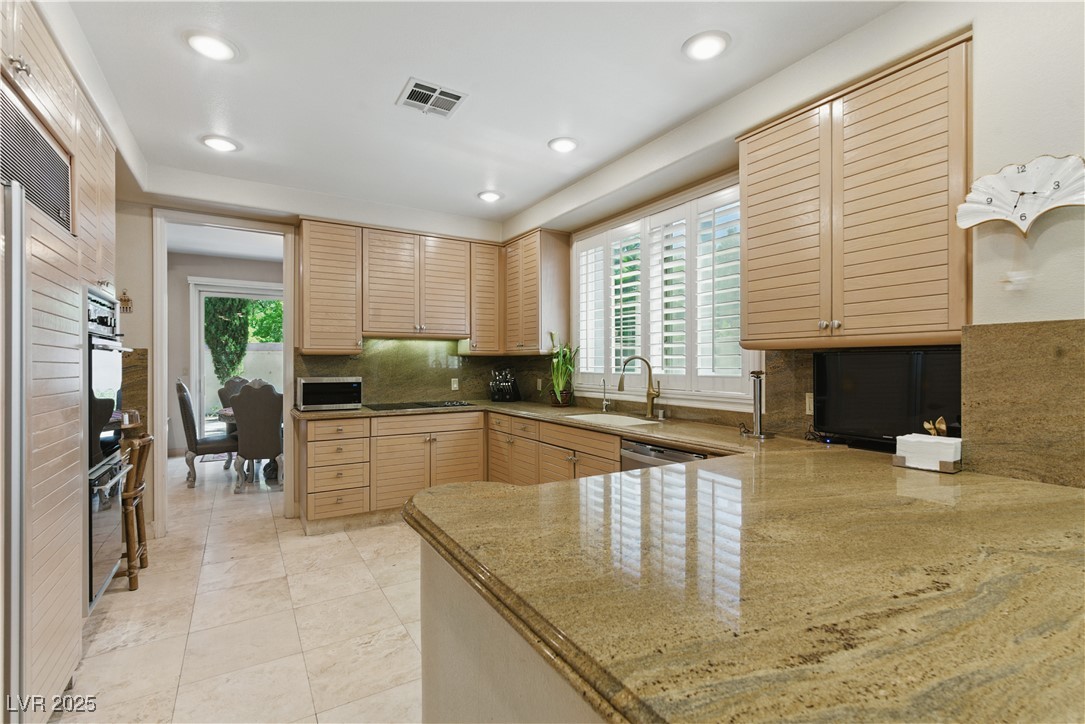 8215 Crow Valley Lane Las Vegas, NV 89113 - Photo 19 of 43 Kitchen with backsplash, plenty of natural light, a peninsula, light stone countertops, and recessed lighting