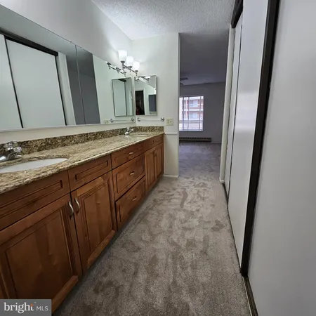 a bathroom with a granite countertop sink a mirror and a shower