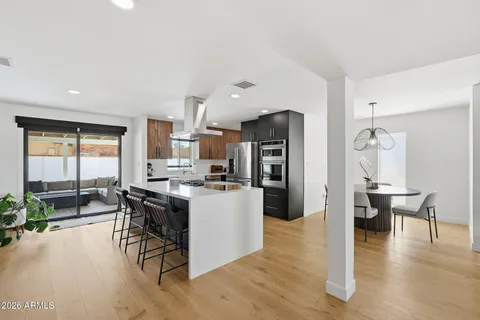 a dining room with wooden floor a chandelier a wooden table and chairs