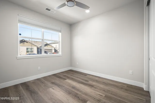 a view of empty room with wooden floor and fan