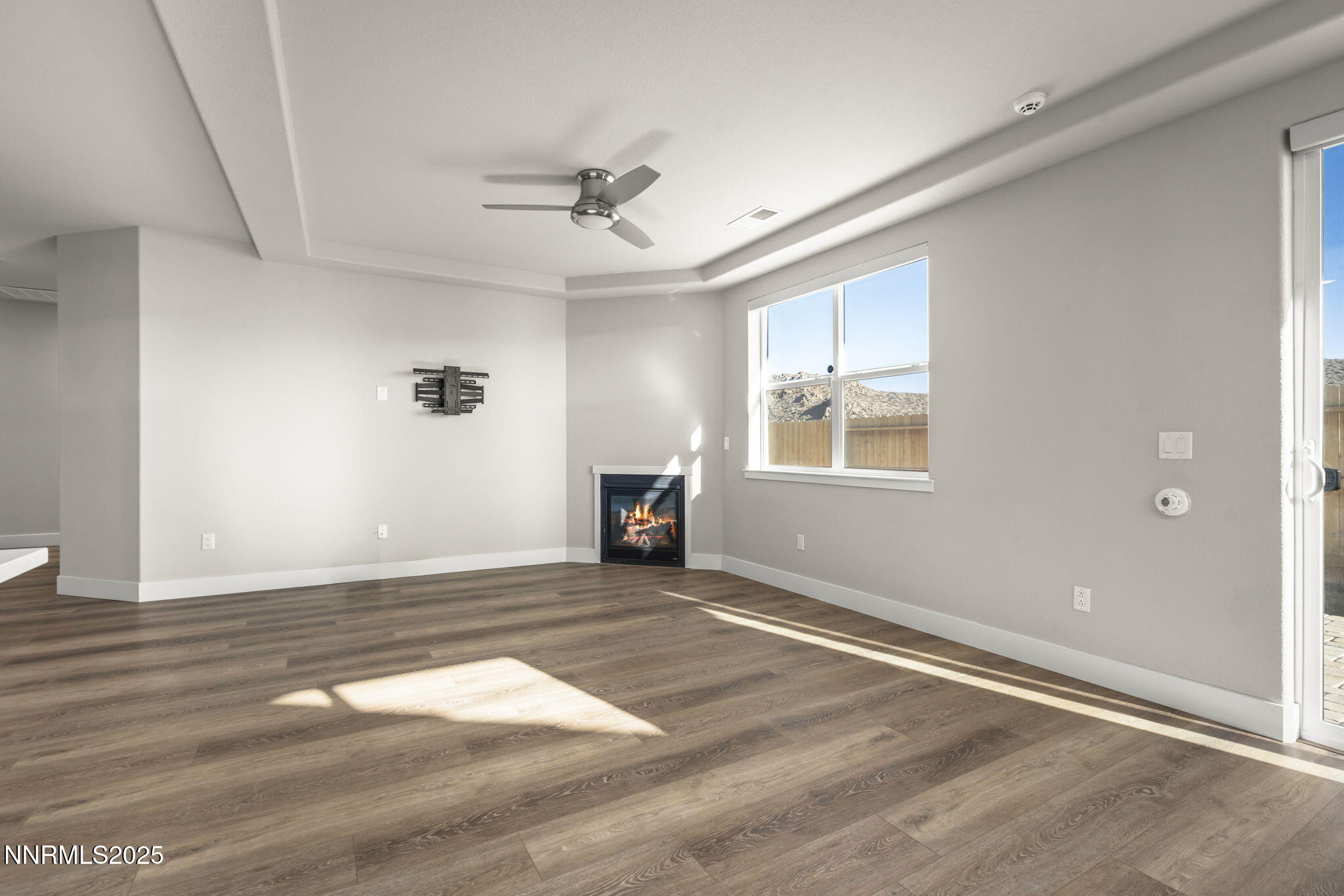 7726 Enclave Key Road Reno, NV 89506 - Photo 6 of 25 an empty room with wooden floor ceiling fan and windows