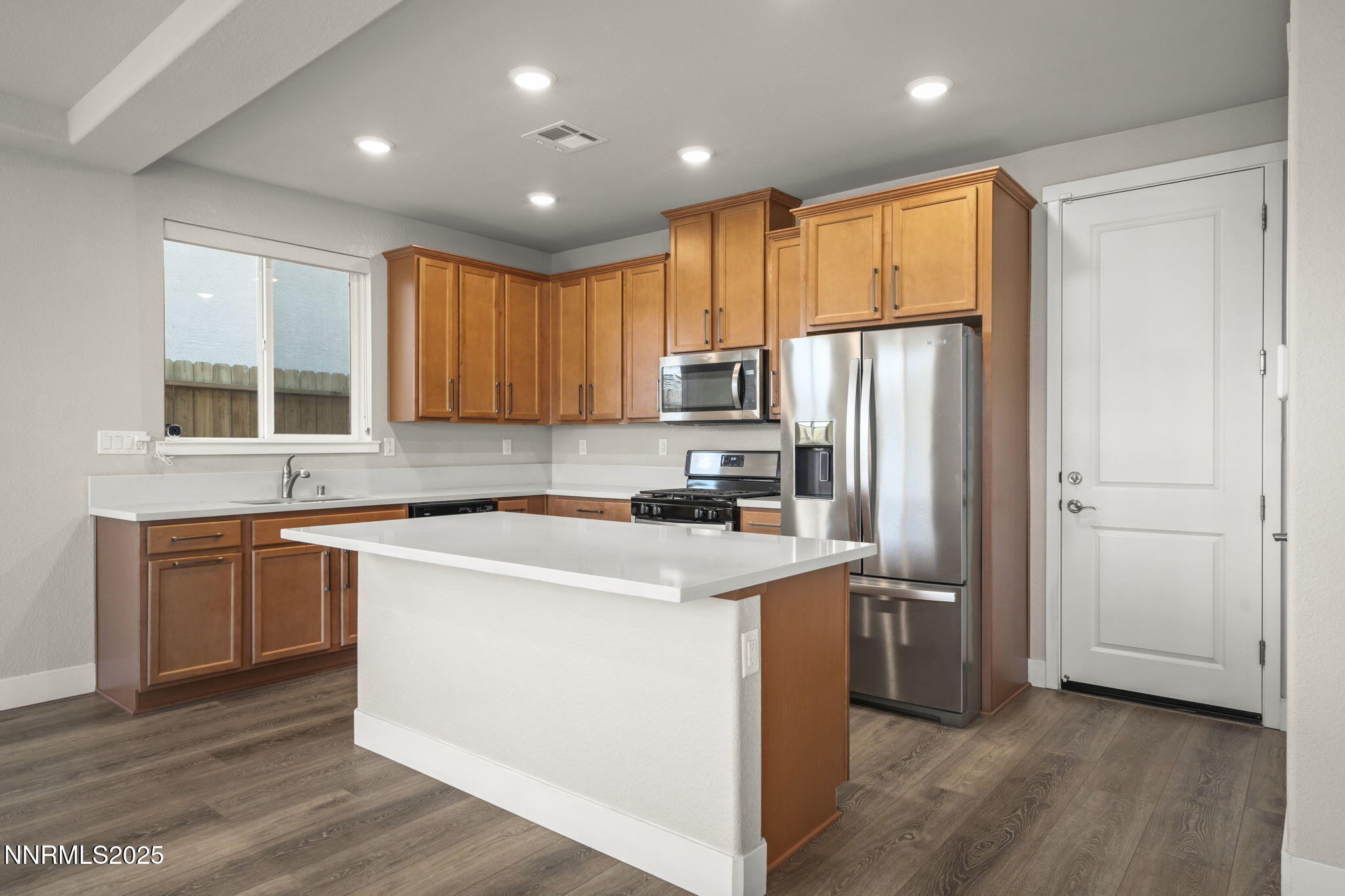 7726 Enclave Key Road Reno, NV 89506 - Photo 9 of 25 a kitchen with stainless steel appliances granite countertop a refrigerator a sink dishwasher a stove and white countertops with wooden floor
