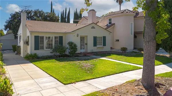 a view of a white house with a swimming pool and a lawn chairs under an umbrella