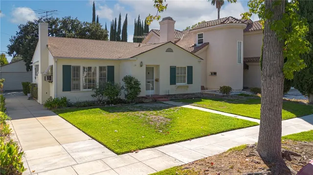 a view of a white house with a swimming pool and a lawn chairs under an umbrella