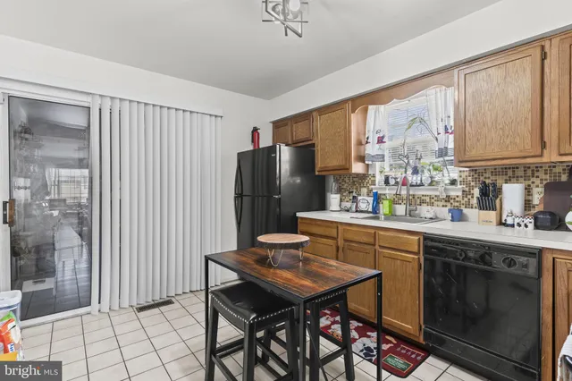 a kitchen with granite countertop a refrigerator a sink dishwasher a stove and a dining table with wooden cabinet