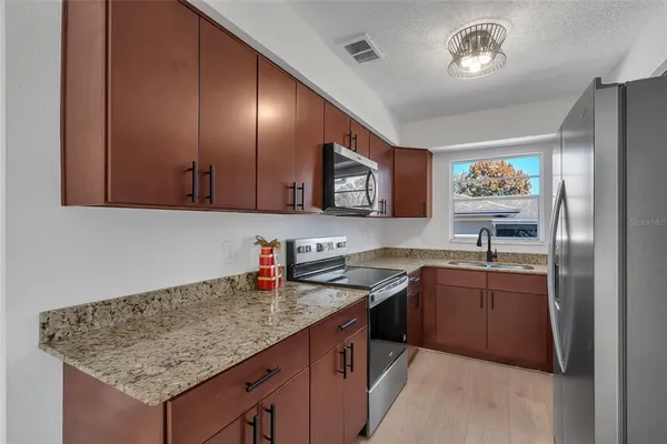 a kitchen with stainless steel appliances granite countertop a sink stove and refrigerator