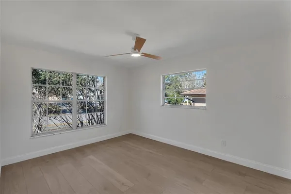 an empty room with windows and fan