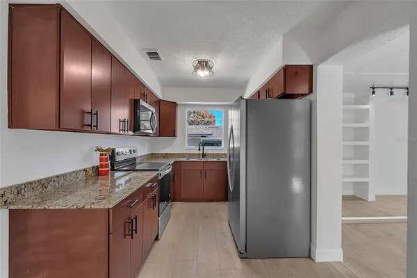a kitchen with stainless steel appliances granite countertop a refrigerator a stove a sink and dishwasher