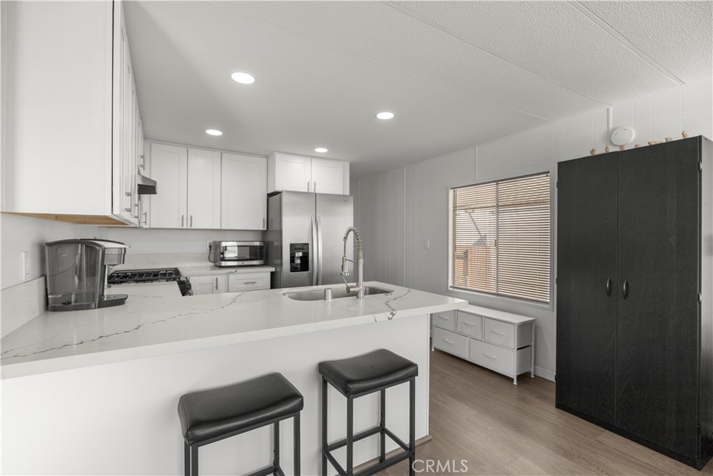27150 Shadel Road, Unit 122 Menifee, CA 92586 - Photo 6 of 26 a kitchen with granite countertop a refrigerator a sink a stove a dining table and chairs