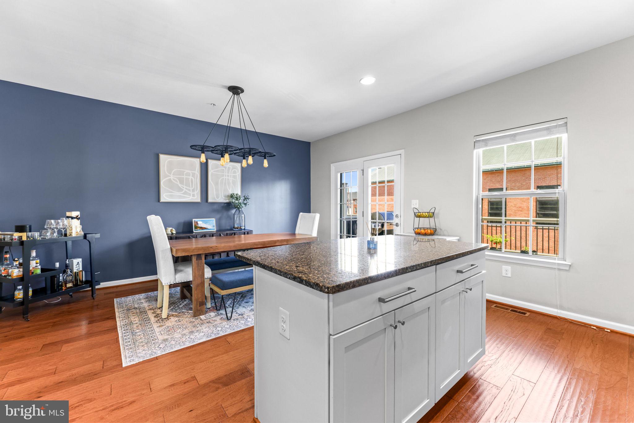 4648 Hudson Street Baltimore, MD 21224 - Photo 14 of 46 a kitchen with stainless steel appliances granite countertop a sink dishwasher a dining table and chairs with wooden floor