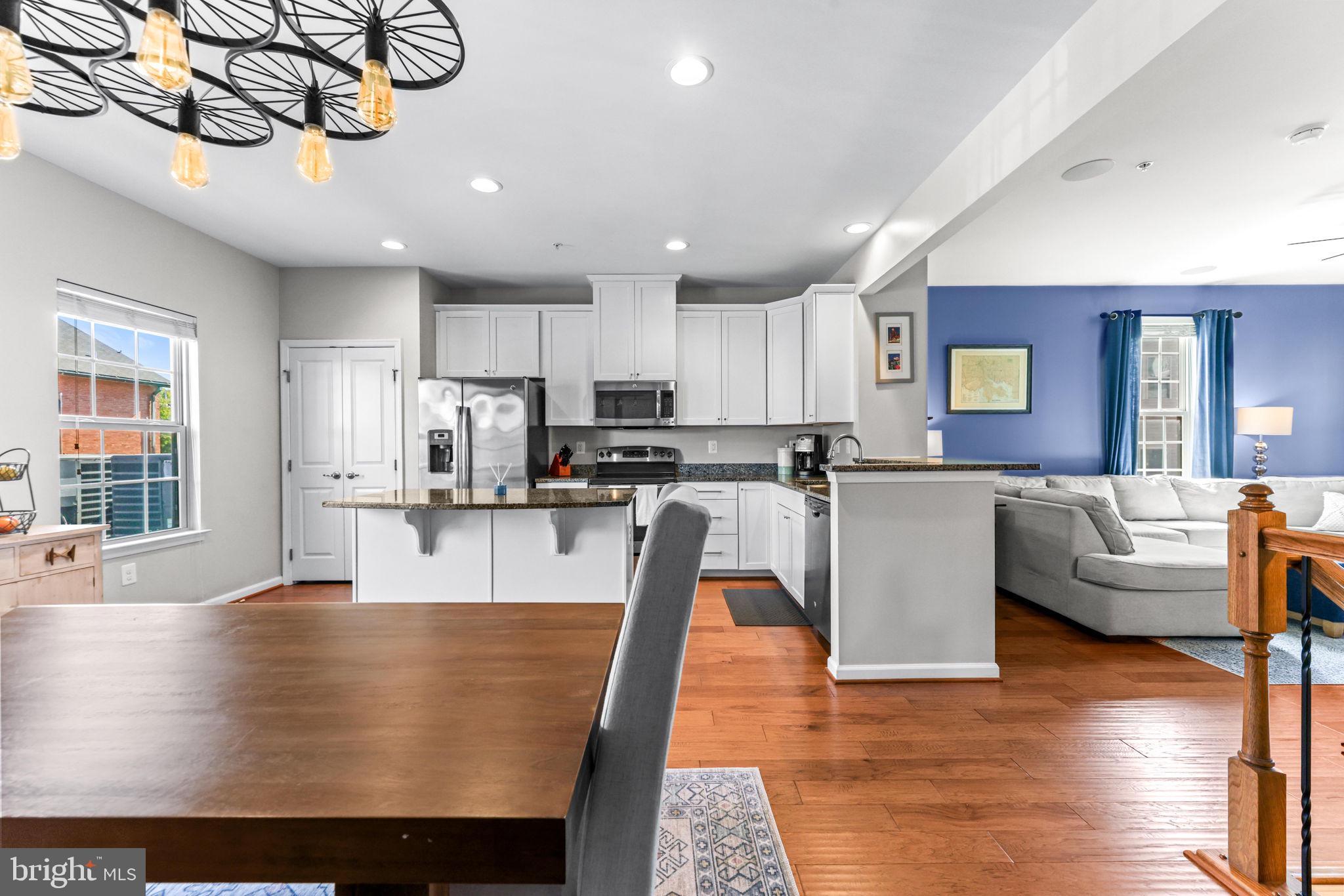 4648 Hudson Street Baltimore, MD 21224 - Photo 18 of 46 a large kitchen with stainless steel appliances granite countertop a sink a stove and a dining table with wooden floor