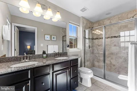 a bathroom with a granite countertop sink toilet a mirror and shower