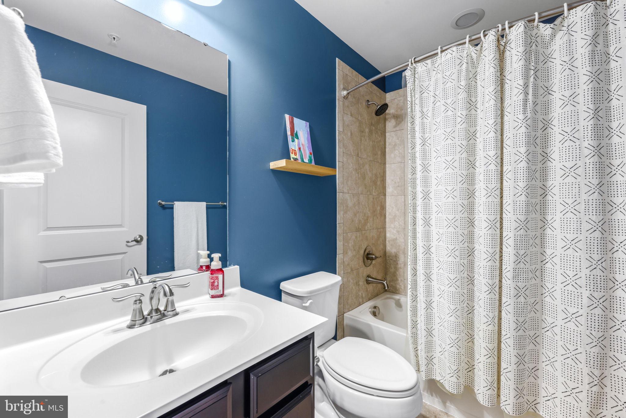4648 Hudson Street Baltimore, MD 21224 - Photo 32 of 46 a bathroom with a sink a toilet and shower curtain