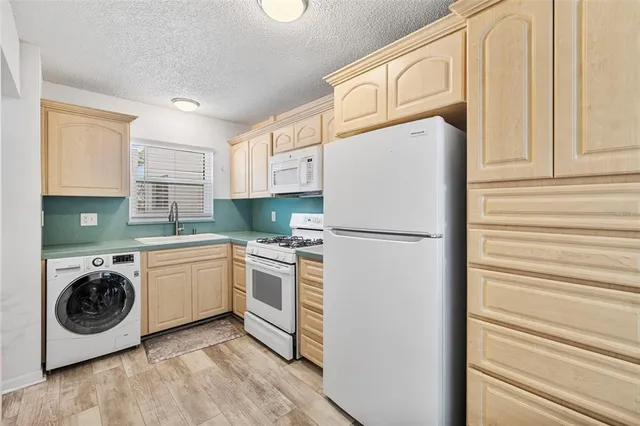 a kitchen with stainless steel appliances granite countertop a refrigerator a washer and dryer