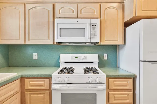 a kitchen with granite countertop white cabinets and white appliances