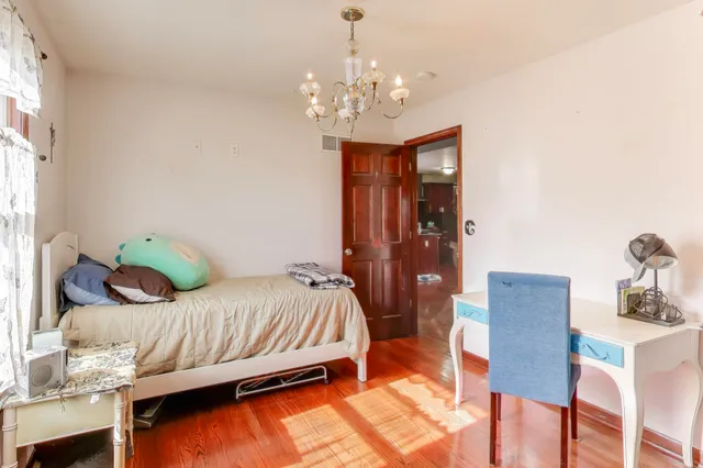 a bedroom with a bed chandelier and a window