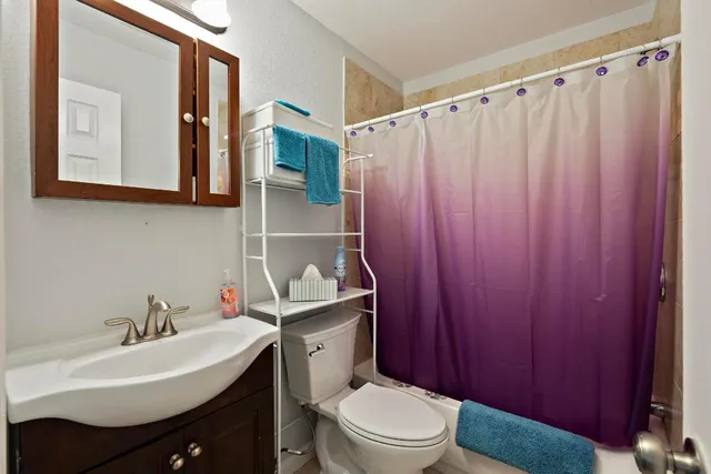 a bathroom with a sink a toilet and shower curtain