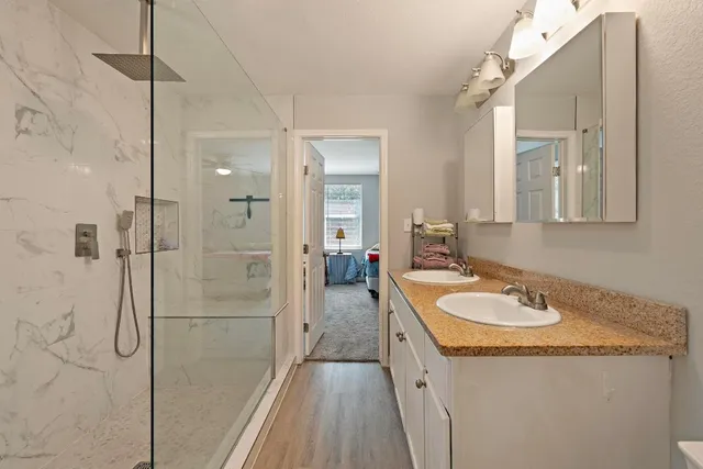 a spacious bathroom with a granite countertop sink a mirror and shower