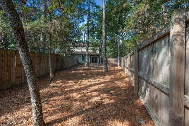 a backyard of a house with lots of plants and large tree
