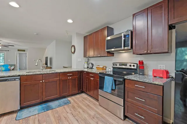 a kitchen with stainless steel appliances granite countertop wooden cabinets a stove top oven a sink and dishwasher