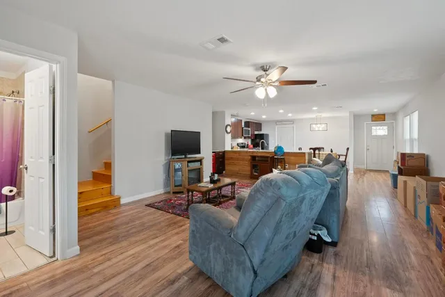 a living room with furniture kitchen view and a wooden floor