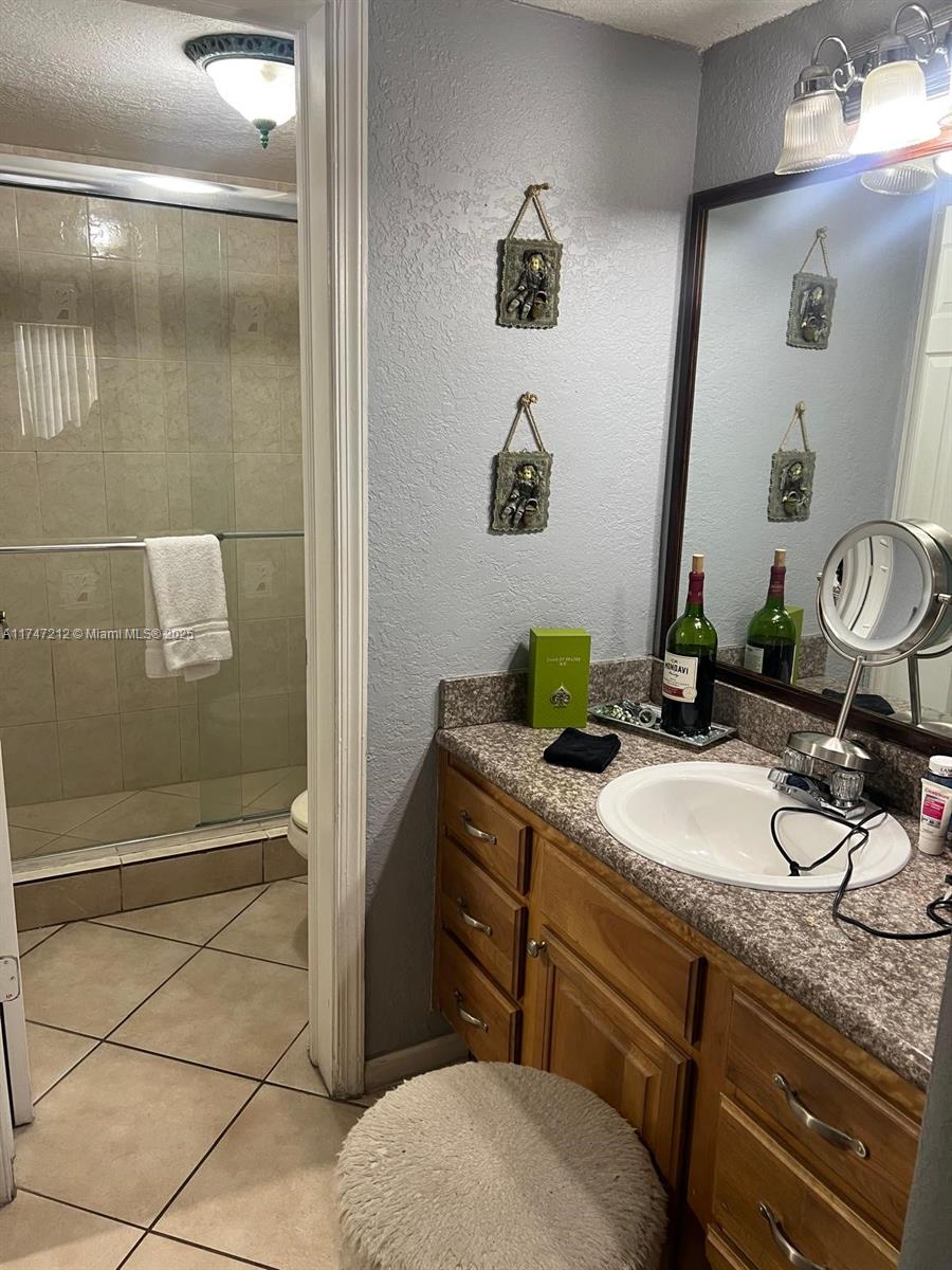 3057 Coral Springs Drive, Unit 102 Coral Springs, FL 33065 - Photo 18 of 26 a bathroom with a granite countertop sink a mirror and shower