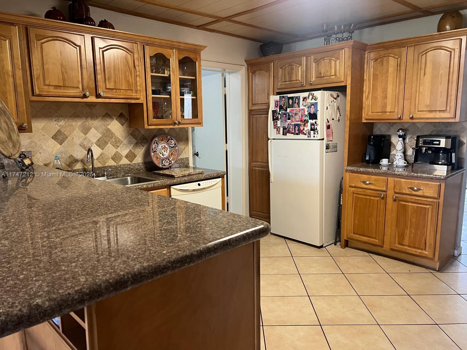 3057 Coral Springs Drive, Unit 102 Coral Springs, FL 33065 - Photo 3 of 26 a kitchen with stainless steel appliances granite countertop a refrigerator a stove and a sink with wooden cabinets