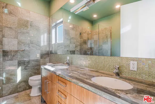 a bathroom with a granite countertop sink a mirror and shower