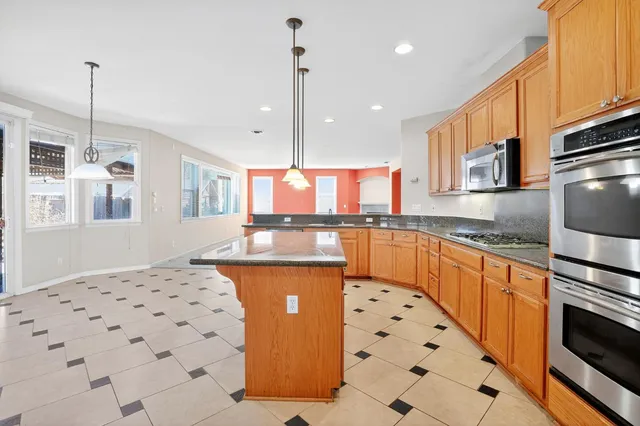 a kitchen with stainless steel appliances kitchen island granite countertop a sink a counter top space cabinets and a window
