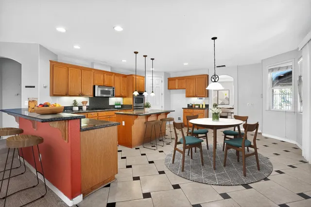 a kitchen with stainless steel appliances kitchen island granite countertop a sink a stove and a refrigerator
