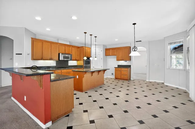 a kitchen with stainless steel appliances kitchen island granite countertop a sink a counter space and cabinets