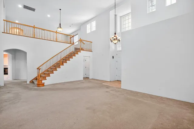 an empty room with stairs and a chandelier fan