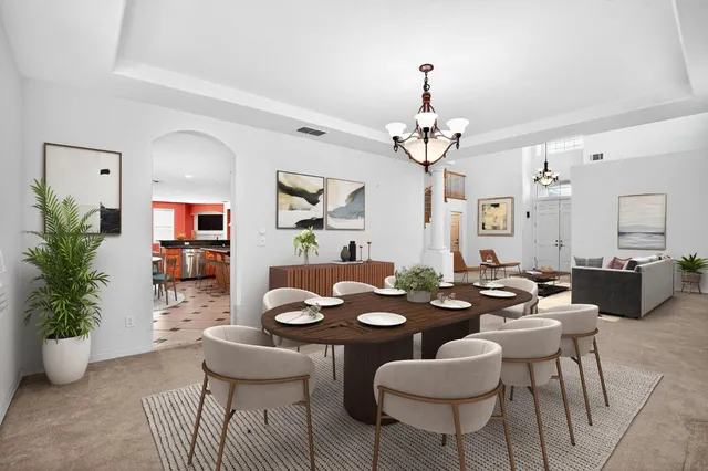 a dining room with wooden floor a chandelier a glass table and chairs