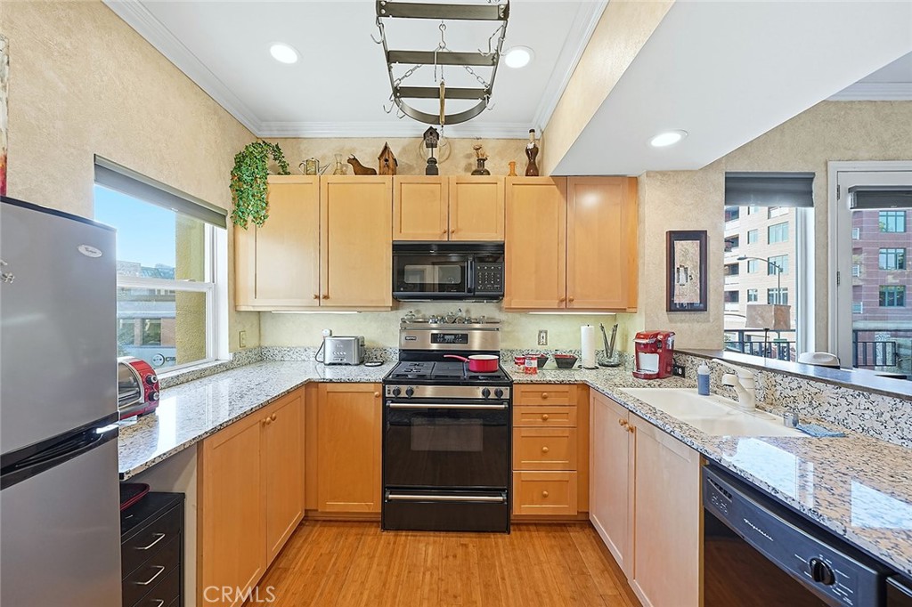 80 North Raymond Avenue, Unit 212 Pasadena, CA 91103 - Photo 10 of 24 a kitchen with stainless steel appliances a sink dishwasher stove and oven with wooden floor