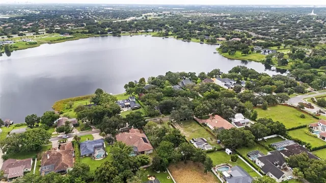 an aerial view of city and lake with trees
