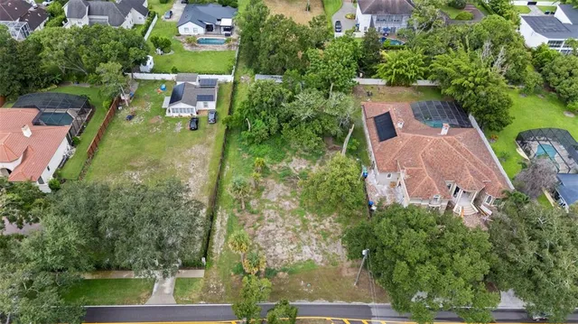 an aerial view of a house with outdoor space and trees all around