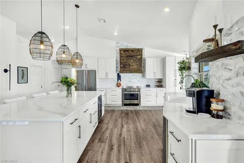 a kitchen with stainless steel appliances kitchen island granite countertop a stove a sink and a white cabinets