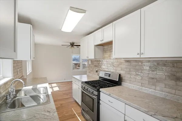 a kitchen with granite countertop a sink stove and cabinets