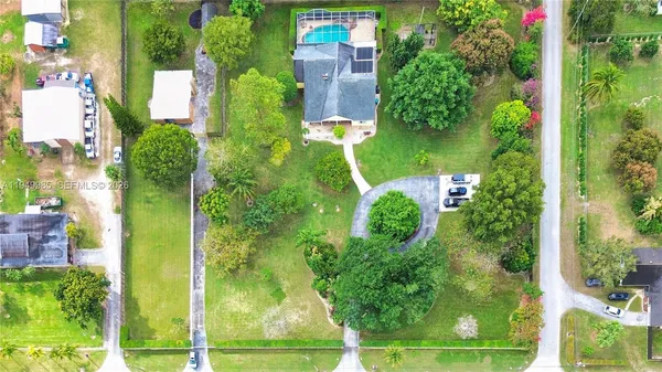 an aerial view of a residential apartment building with a yard and large trees