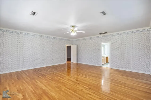 a view of an empty room with window and wooden floor