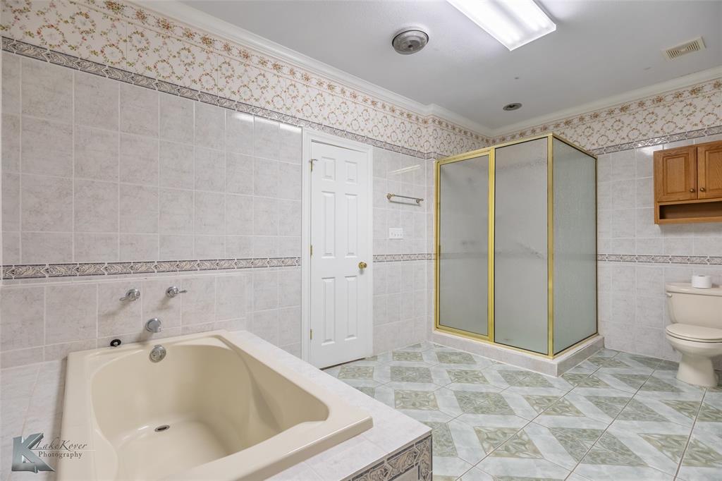 13063 Rainey Ridge Lane Abilene, TX 79602 - Photo 27 of 40 a bathroom with a tub a toilet and a shower
